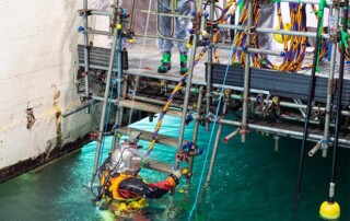 UCC diver in full gear decending via stairs into pile fuel storage pond at Sellafield nuclear power plant.