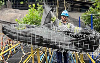 UCC team member preparing a gabion rock basket prepared with geotextile grout bags for concrete retaining wall repair.